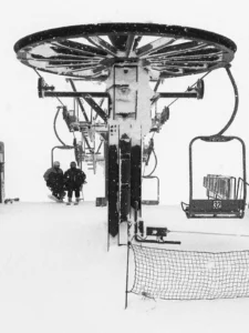 Chairlift bullwheel and empty chairs in heavy snow and wind in Niseko