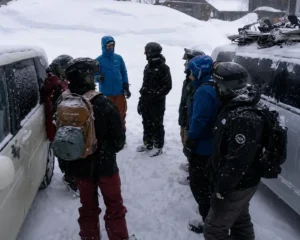 Group of snowboarders gearing up beside vans before a backcountry day in heavy snow