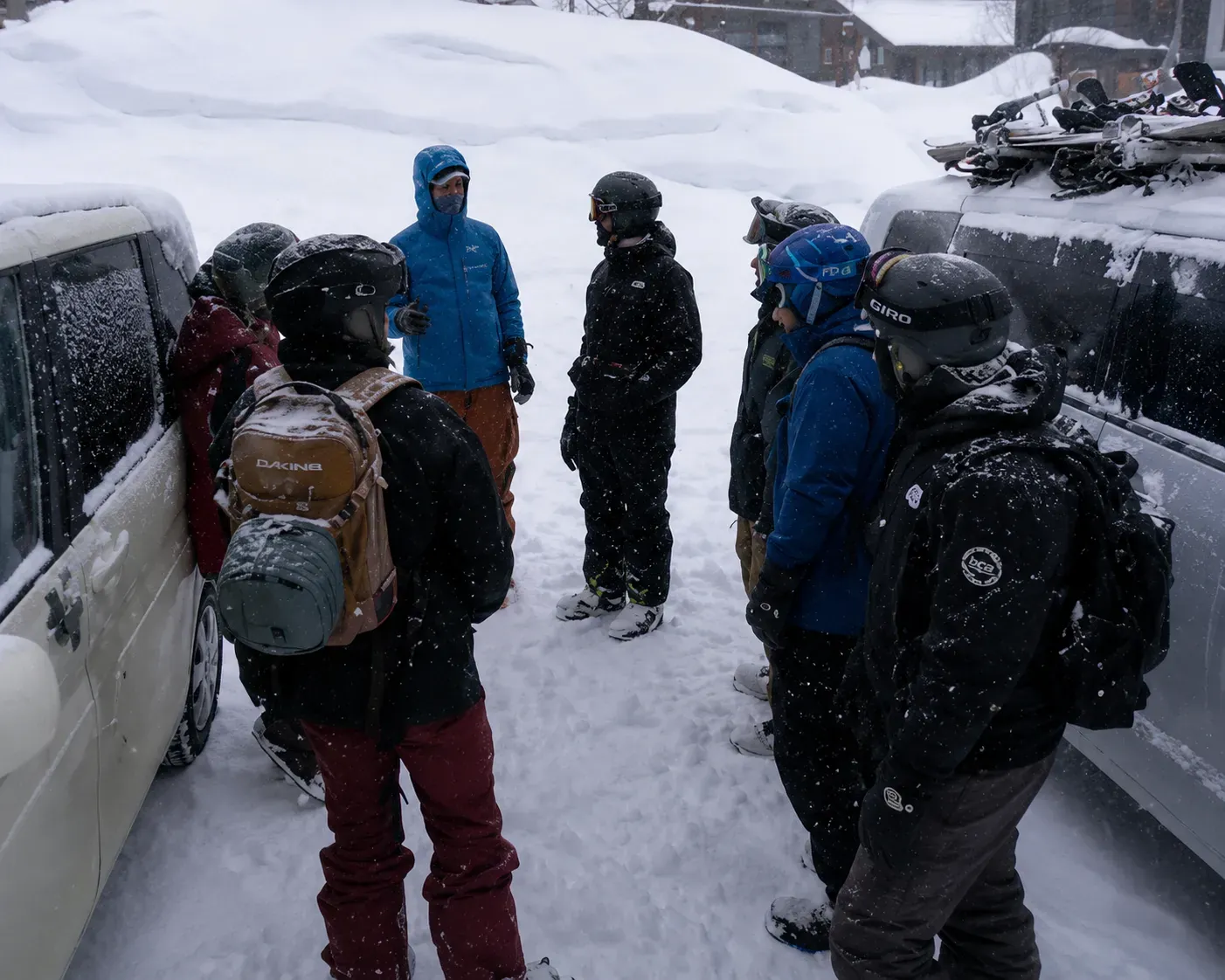 Group of snowboarders gearing up beside vans before a backcountry day in heavy snow
