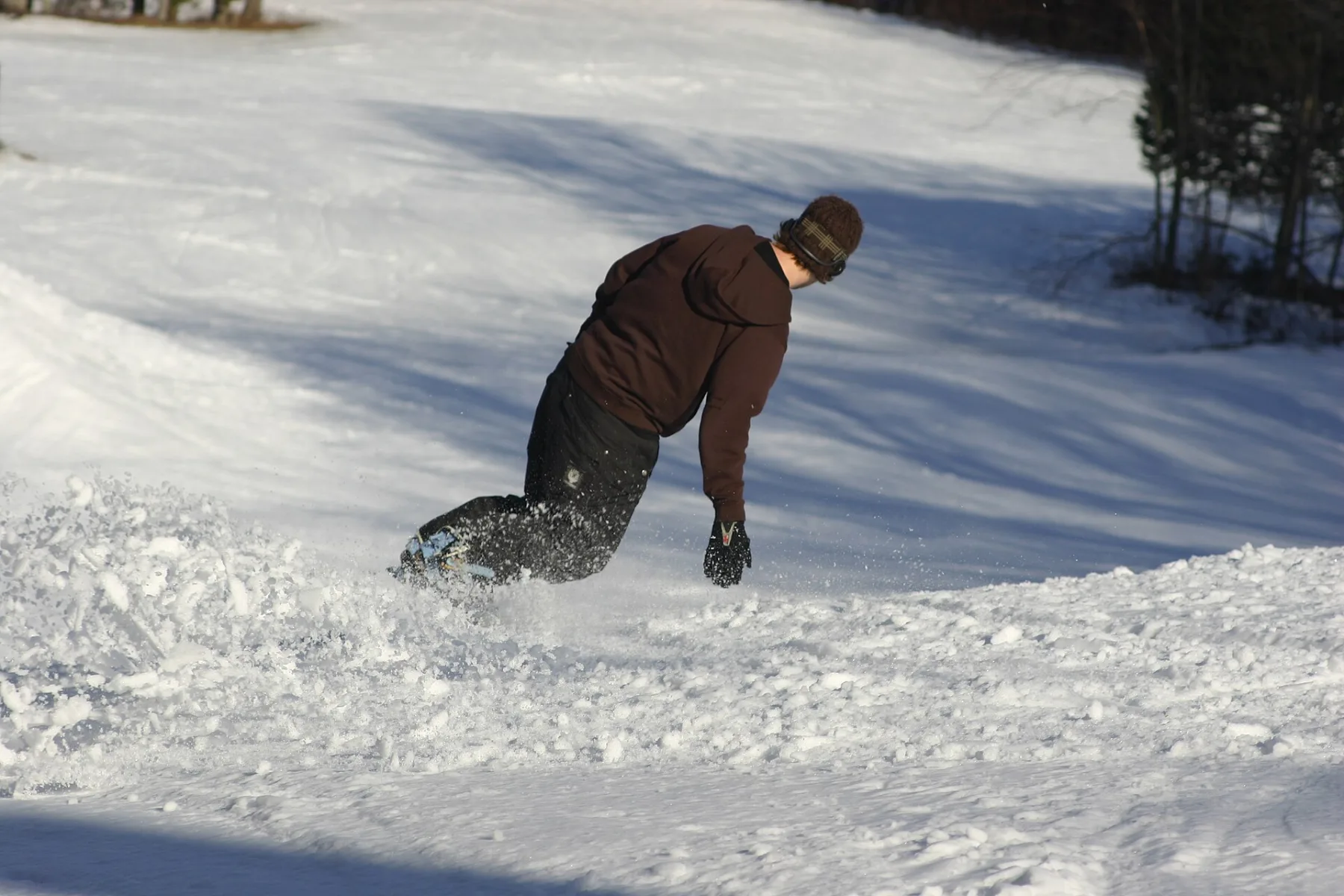 Snowboarder laying over a heelside carve on a groomed slope
