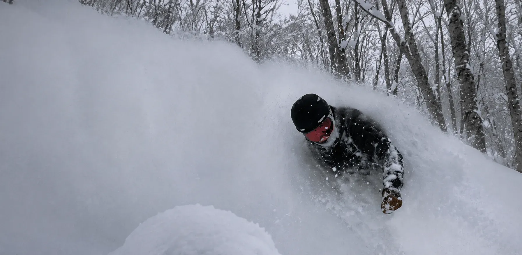 Snowboarder buried to the chest in deep powder with snow flying over the face